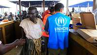 Flüchtlinge und UNHCR-Mitarbeiter in einem Flüchtlingscamp.
