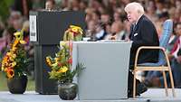 Helmut Schmidt sitzt und spricht in ein Mikrofon, im Hintergrund sitzen viele Personen