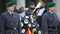 Soldaten neben einem Gedenkkranz.