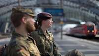 Soldatin und Soldat sitzen auf einer Bank im Bahnhof