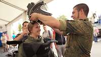 Soldaten ziehen Besucherin Schutzanzug an