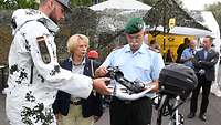 Soldaten und Besucher neben Exponaten