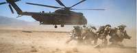 Soldaten hocken vor einem startenden Transporthubschrauber vom Typ CH-53