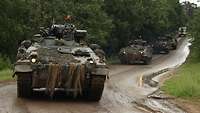 Panzer fahren als Kolonne eine Straße entlang