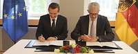 Gerd Hoofe und Lionel Souque sitzen nebeneinander und unterzeichnen eine Kooperationsvereinbarung