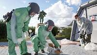 Drei Personen in Schutzkleidung