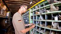 Soldat steht vor einem Materialregal in einem Container