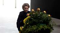 Ministerin Von der Leyen kniet vor einem Kranz