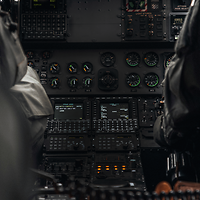 Die Mittelkonsole eines Hubschraubers ist zu erkennen, flankiert von dem Piloten und Copiloten.