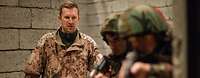 Ein deutscher Soldat steht hinter zwei bewaffneten kurdischen Soldaten 