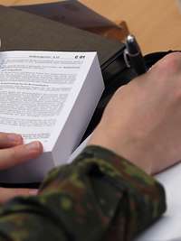 Soldat schreibt sich Informationen aus dem Soldatengesetz raus.