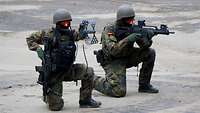 Soldaten knien mit ihren Waffen auf einem Flugfeld
