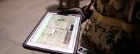 Soldat hält ein Tablet, auf dem eine Karte zu sehen ist, in der Hand.