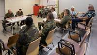 Mehrere Soldaten und Zivilbeschäftigte der Bundeswehr sitzen in einem Vortragsraum