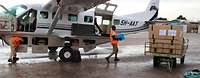 Einheimischer trägt einen Karton von einem kleinen Flugzeug zum Anhänger