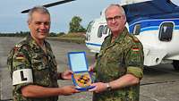 Marlow und Zorn halten das Wappen des Generalinspekteurs der Bundeswehr in den Händen