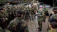 General Zorn steht zwischen den Soldaten vor den Fahrzeugen