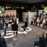 Von der Leyen auf den Bildschrimen in einer Diskussionsrunde
