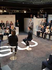 Von der Leyen auf den Bildschrimen in einer Diskussionsrunde