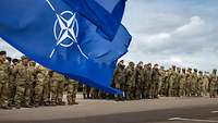 Angetretene Soldaten, im Vordergrund NATO-Flagge