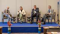 Drei Männer und eine Frau bei einer Podiumsdiskussion