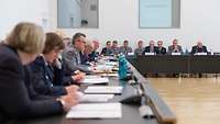 Soldaten und Zivilisten sitzen in einem Konferenzraum