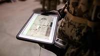 Ein Soldat der Bundeswehr hält ein Tablet in den Händen
