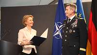 Von der Leyen überreicht einem Soldaten eine Urkundenmappe
