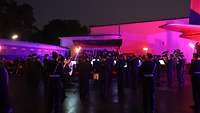 Soldaten mit Musikinstrumenten vor einer Tribühne in der Dämmerung