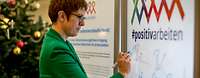 Ministerin Kramp-Karrenbauer unterschreibt auf einer Plexiglaswand miot Aufschrift positivarbeiten