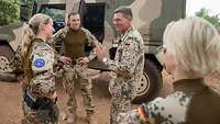 Drei Bundeswehrsoldaten sprechen miteinander vor einem Militärfahrzeug