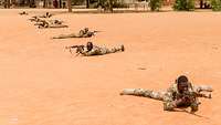 Malische Soldaten liegen mit Waffen auf dem Boden