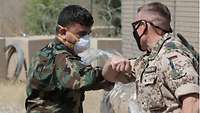 Ein deutscher und ein afghanischer Soldat begrüßen sich mit den Ellenbogen