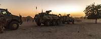 Drei gepanzerte Militärfahrzeuge fahren hintereinander bei Dämmerung
