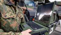 Ein Bundeswehrsoldat hält einen Laptop