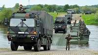 Militärfahrzeuge fahren über ein Schwimmbrücke aus Amphibien M3