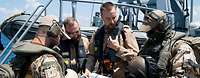 Vier Soldaten besprechen sich an Deck eines Schiffes