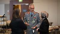 Brigadegeneral Arlt im Dienstanzug im Gespräch mit zwei Damen, die von hinten zu sehen sind.