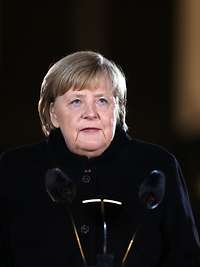 Angela Merkel spricht in ein Mikrofon bei Dunkelheit.