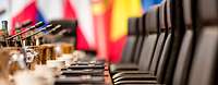 Ein leerer Konferenztisch und Flaggen unscharf im Hintergrund