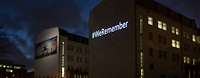 Schrift-Projektion „WeRemeber“ an einem Gebäude bei Dunkelheit