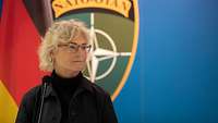 Ministerin Lambrecht steht vor einem Mikrofon. Im Hintergrund die Deutschlandflagge und das EFP-NATO-Wappen.