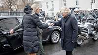 Ministerin Christine Lambrecht begrüßt Kajsa Ollongren mit Ghettofaust vor einem Auto 