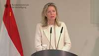 Kajsa Ollongren steht an einem Rednerpult mit Mikrofon und spricht