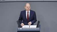 Ein Porträt von Kanzler Scholz, der am Rednerpult im Bundestag spricht.