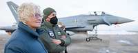 Ministerin Lambrecht steht neben einem Soldaten. Im Hintergrund steht ein Kampfflugzeug Eurofighter.