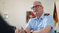 Generalinspekteur Zorn sitzt an einem Tisch und spricht mit einer Person.