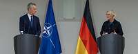 Ministerin Lambrecht und Jens Stoltenberg stehen jeweils an einem Rednerpult vor den Flaggen von Deutschland und der NATO.