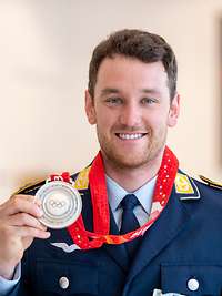 Der Athlet Julian Rauchfuss hält seine Silber-Medaille hoch.