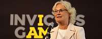 Ministerin Lambrecht spricht am Mikrofon vor dem Schriftzug Invictus Games.